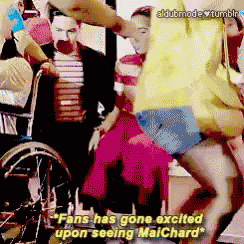 a woman in a yellow shirt is dancing in front of a man in a wheelchair who says fans has gone excited