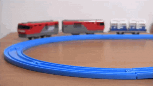 a toy train is going down a blue track on a table .