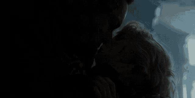 a man and woman are kissing in the dark in a dark room .