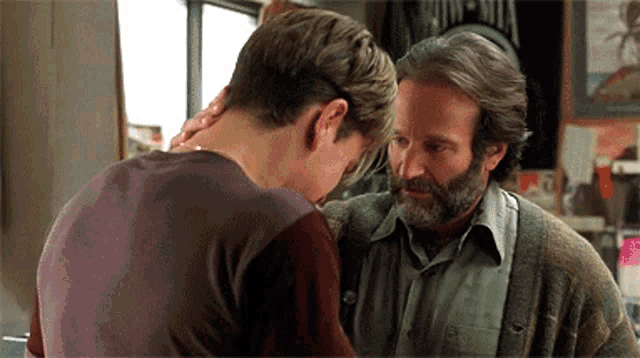 a man with a beard is standing next to a younger man