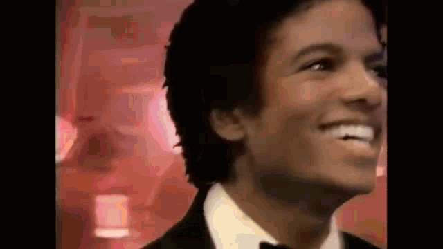 a close up of a man wearing a tuxedo and bow tie smiling .