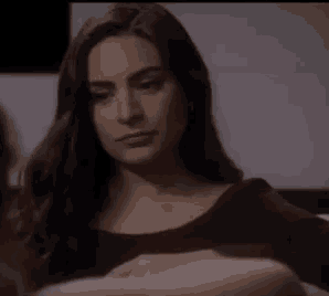 a woman with long dark hair is sitting on a couch and smiling .