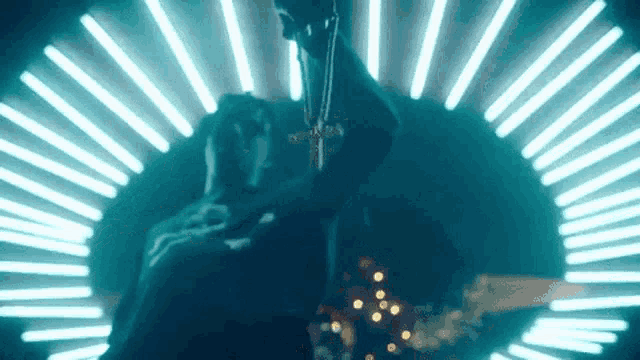 a person holding a cross in front of a circle of neon lights