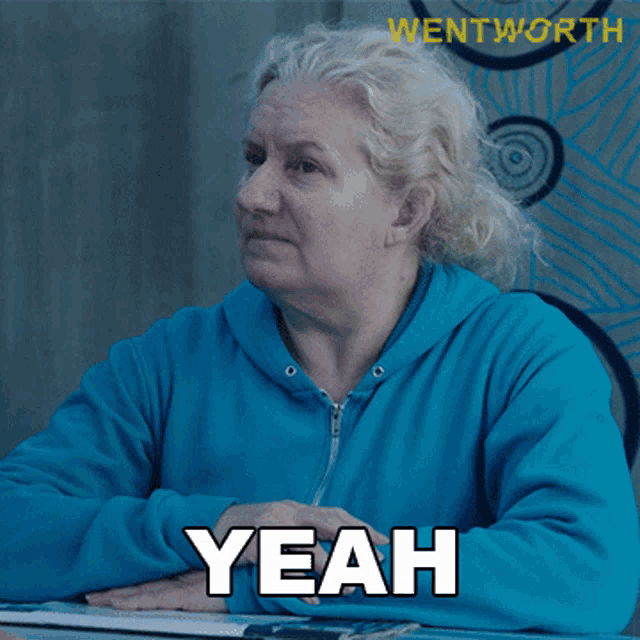 a woman in a blue sweatshirt says yeah in black letters