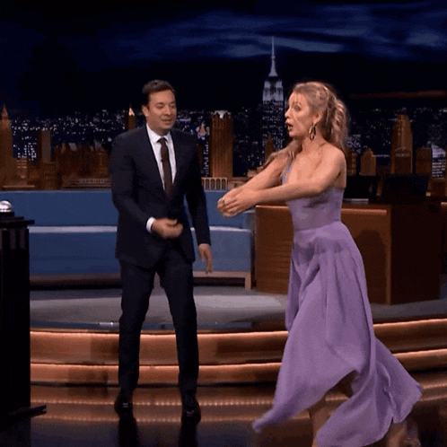 a woman in a purple dress is dancing on a stage with a man in a suit