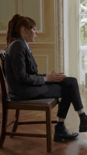 a woman sits in a chair with her legs crossed
