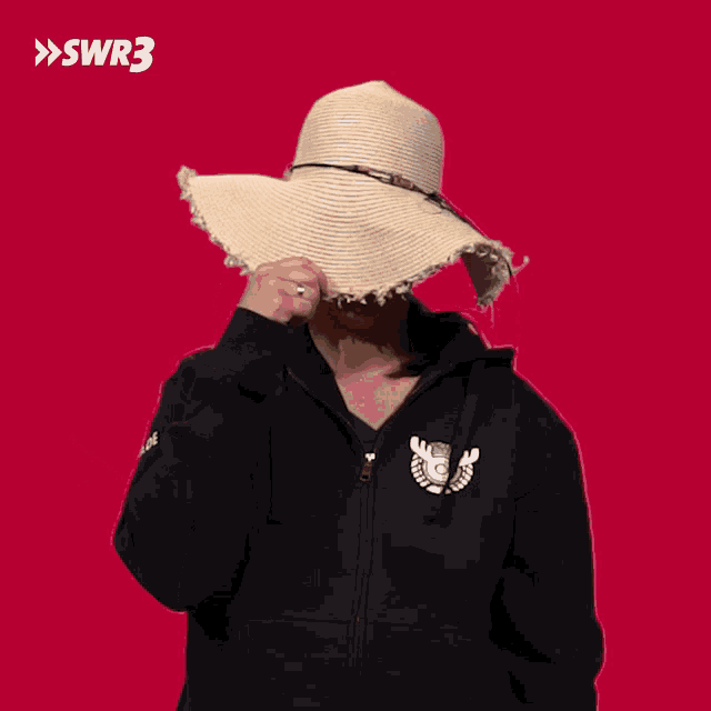a woman wearing a black hoodie and a straw hat with swr3 on the bottom