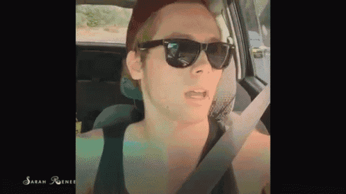 a man wearing sunglasses and a hat is sitting in a car .