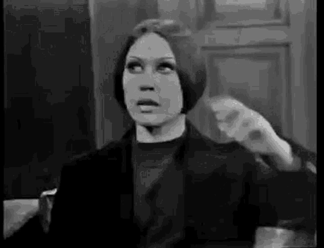 a black and white photo of a woman in a black coat holding a brush .