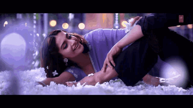 a woman in a purple top is laying on a bed with her legs crossed
