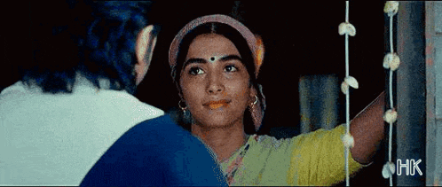 a woman with a bindi on her forehead is standing next to a man and looking at him .