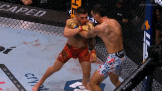 two men are fighting in a boxing ring with the word caped on the wall behind them .