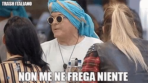 a man wearing a blue turban and sunglasses is talking to two women and says non me ne frega niente .
