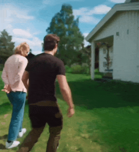 a man and woman are walking towards a white house