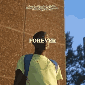 a young man wearing a yellow shirt and a blue backpack is standing in front of a brick building .