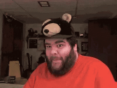 a man with a beard wearing a teddy bear hat is making a funny face .