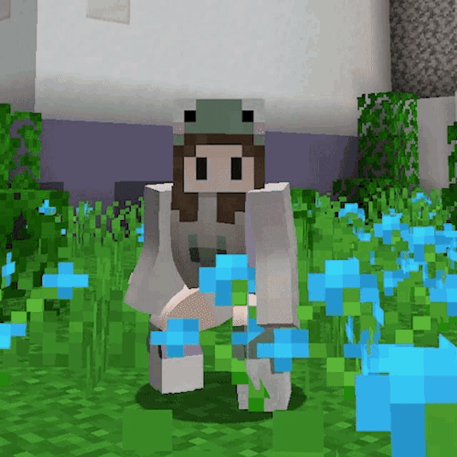 a girl in a frog hat is kneeling in a field of flowers