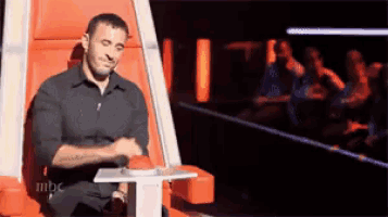 a man is sitting in a chair pressing a button on a table