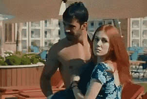 a man and a woman are standing next to each other in a pool .