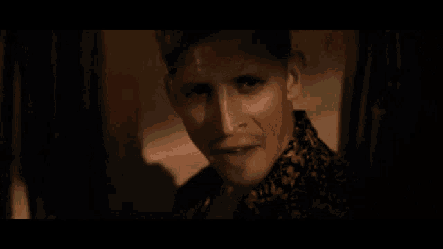 a close up of a man 's face in a dark room with a shadow on the wall .