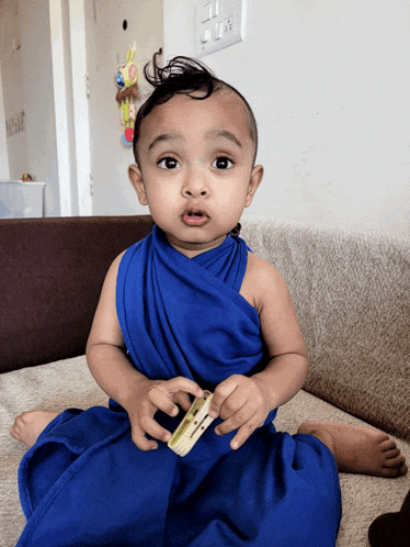 a baby is sitting on a couch with a blue cloth around his neck
