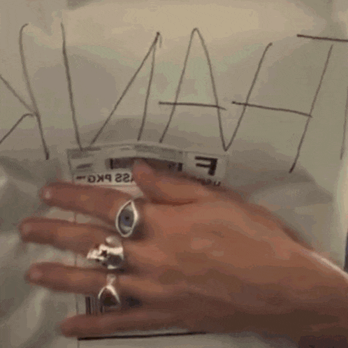 a close up of a person 's hand holding a piece of paper with the letter f on it