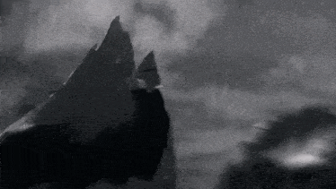 a black and white photo of a mountain and a boat in the rain .