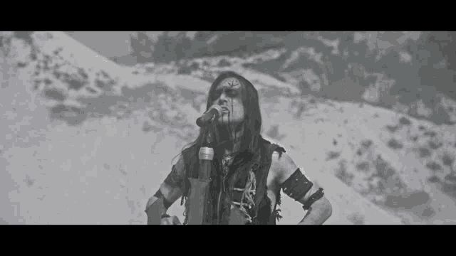 a black and white photo of a man singing into a microphone in the snow