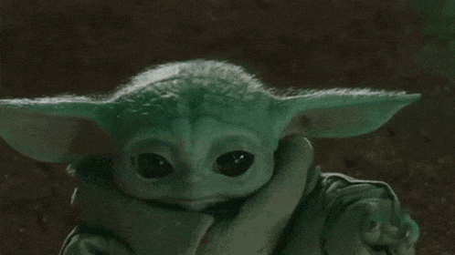 a close up of a baby yoda from star wars with a scarf around his neck .