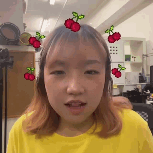 a girl wearing a yellow shirt has cherry stickers on her forehead