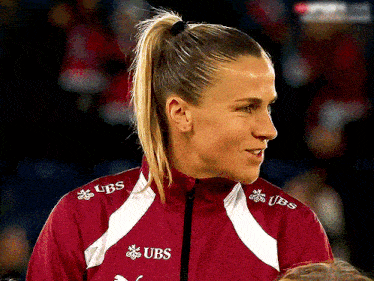 a woman wearing a red jacket with ubs written on it