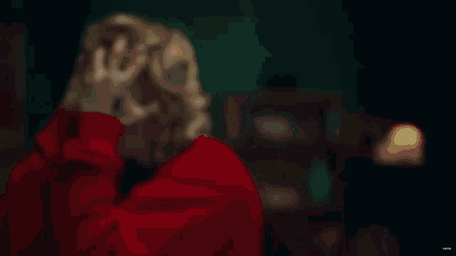 a blurry picture of a woman in a red shirt with blonde hair .