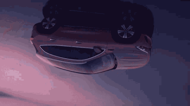 a car is upside down in the air with a purple sky in the background