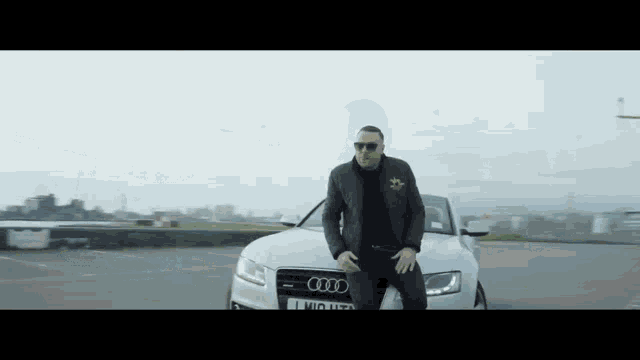 a man sitting on the hood of an audi car