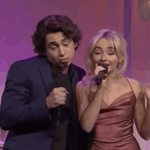 a man and a woman are singing into microphones while standing next to each other .