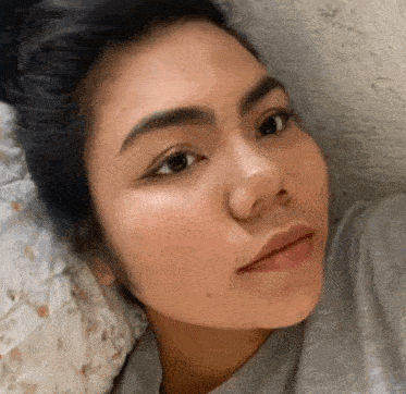 a close up of a woman 's face while laying on a pillow .
