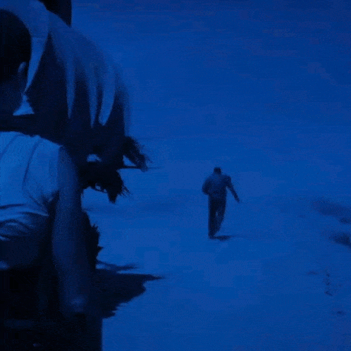 a man in a white shirt is walking through a snowy field