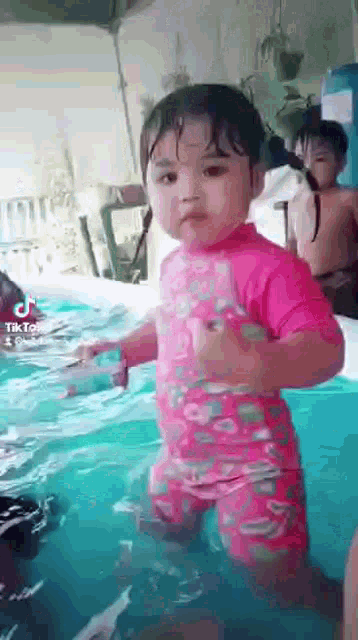 a little girl is standing in a pool of water .