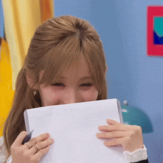 a woman is holding a piece of paper in front of her face