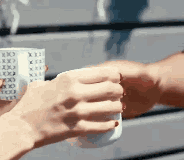 a man and a woman are holding cups of coffee and toasting .