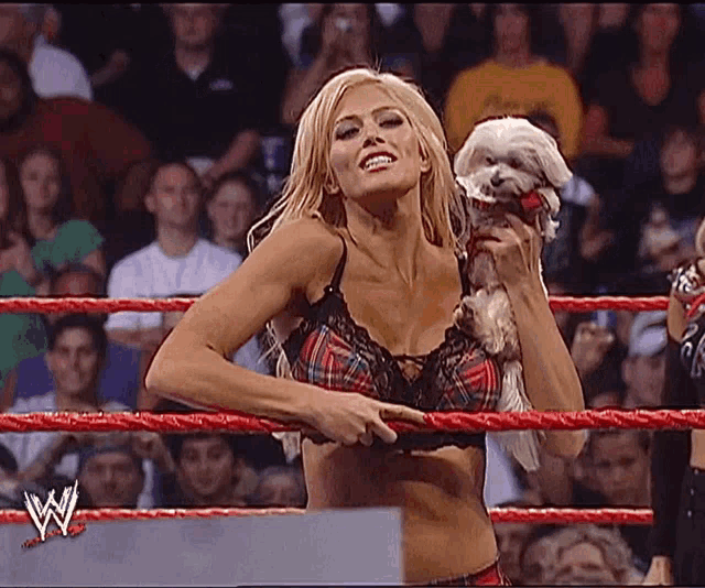 a woman in a wrestling ring holds a small dog
