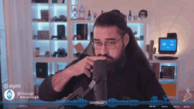 a man with glasses and a beard is sitting in front of a microphone with a blue background