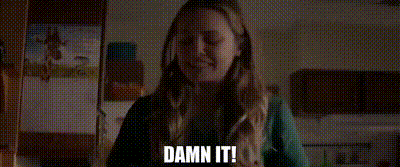 a woman is sitting in a dark room smoking a cigarette and says `` damn it '' .