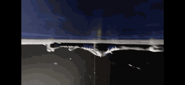 a drop of water is falling into a black surface