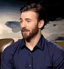 a man with a beard is wearing a blue shirt and smiling .