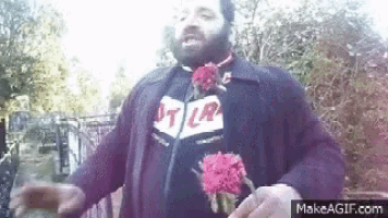 a man with a beard is holding a bunch of flowers in his hand .