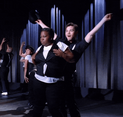 a man in a wheelchair is dancing with a woman in a top hat