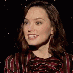 a close up of a woman 's face with a striped shirt on making a funny face .