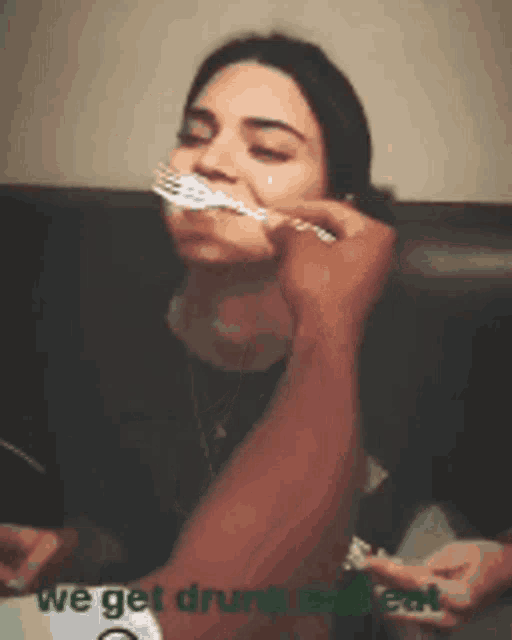 a woman with a spoon in her mouth is being fed by a man with the words we get drunk and eat below her