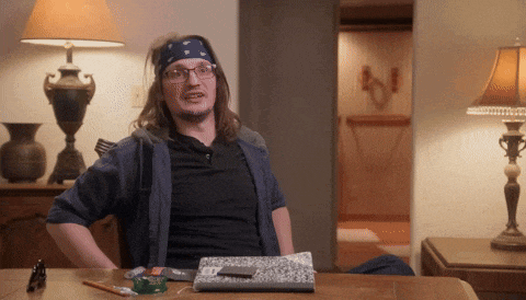 a man with glasses and a bandana on his head sits at a table